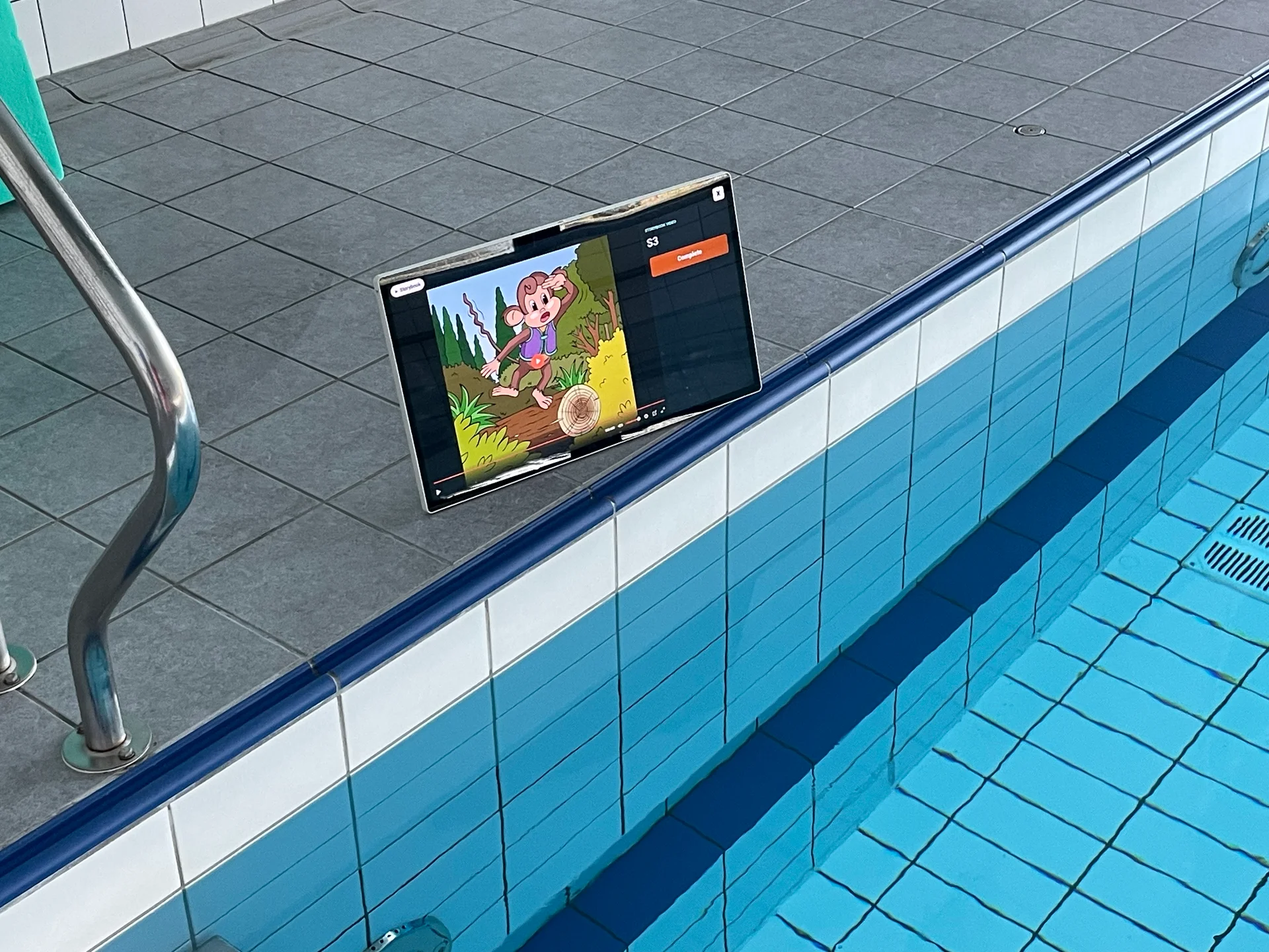 Tablet beside a swimming pool showing a Studio storybook illustration